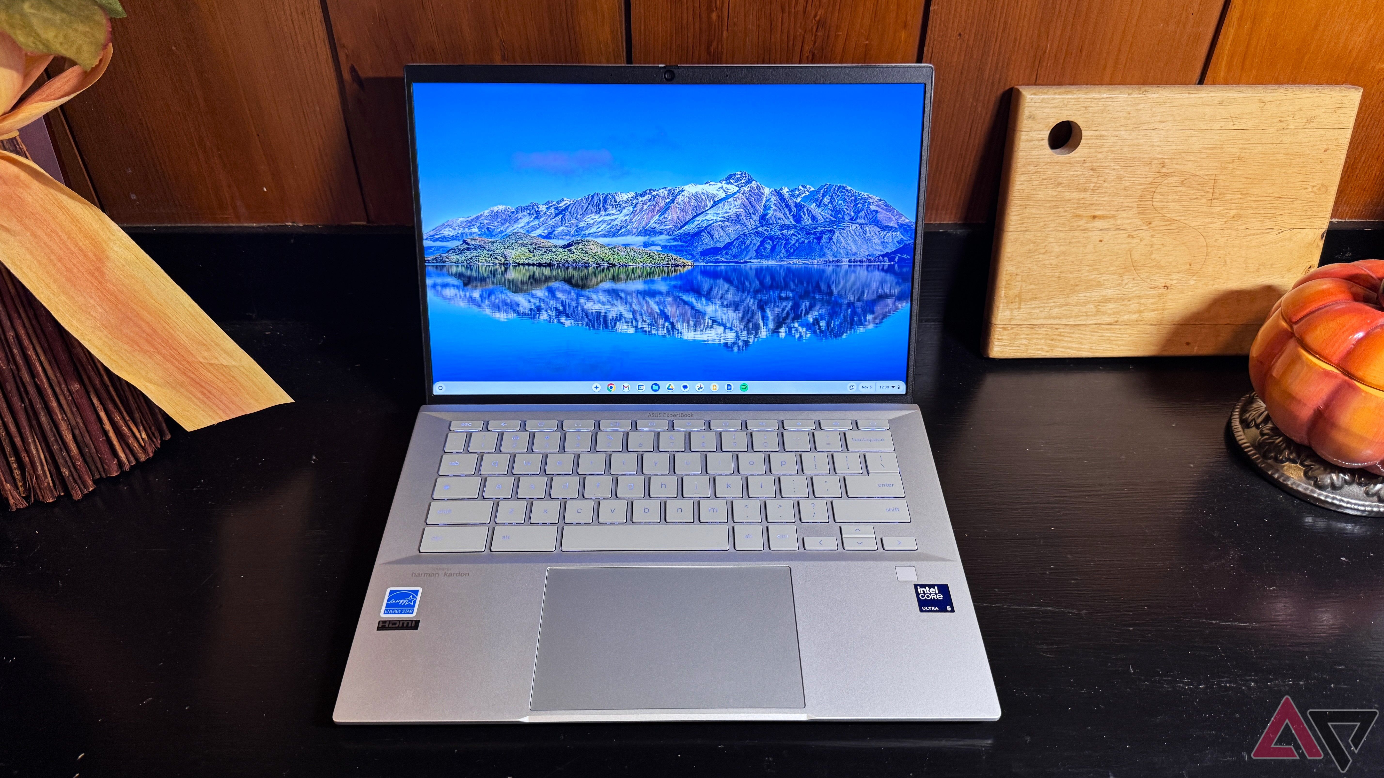 Asus Chromebook Plus CX54 em uma superfície preta com fundo marrom claro ao lado de uma tábua de madeira.