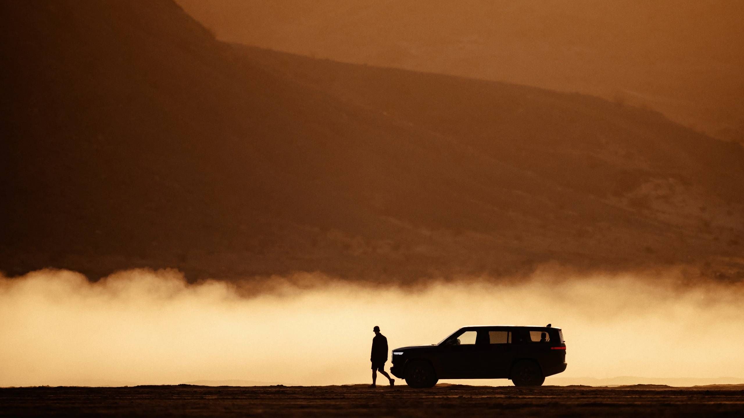 Uma imagem distante de um SUV visto de lado, em frente a uma montanha