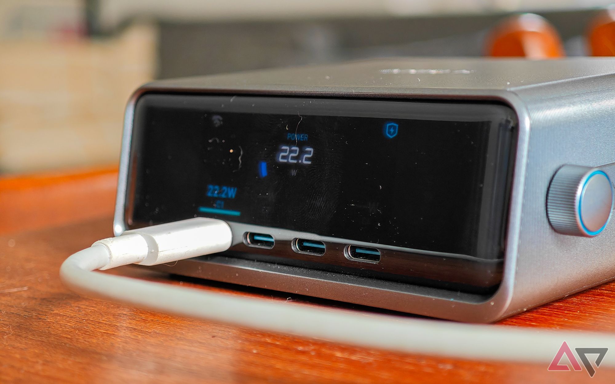 Carregador de mesa Anker Prime 250 W sobre uma mesa de madeira com um cabo branco conectado a uma porta USB-C