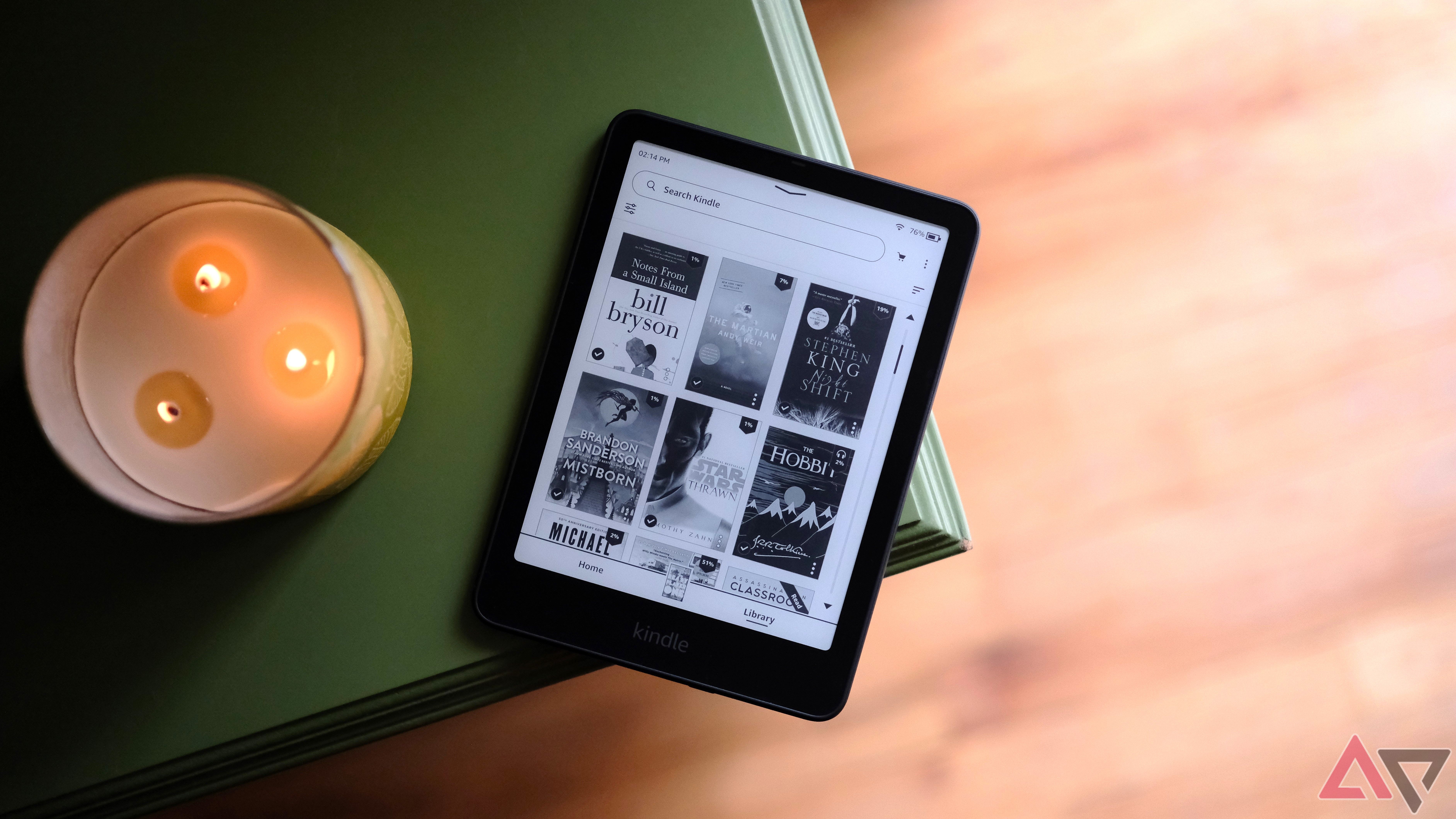 Kindle Paperwhite (2024) deitado na borda da mesa mostrando uma tela com seleção de livros