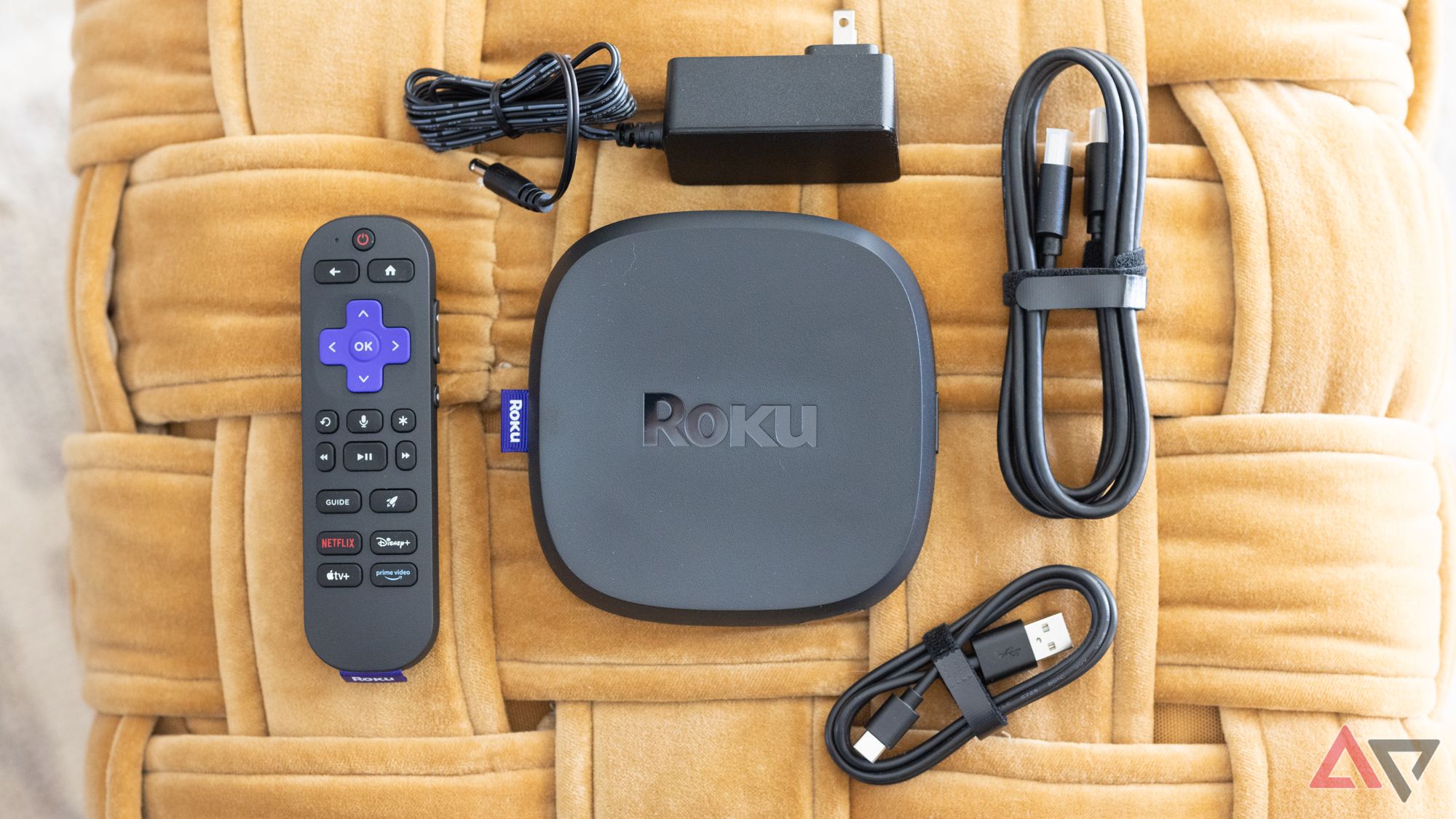 Um Roku Ultra com todos os seus acessórios em uma superfície tecida