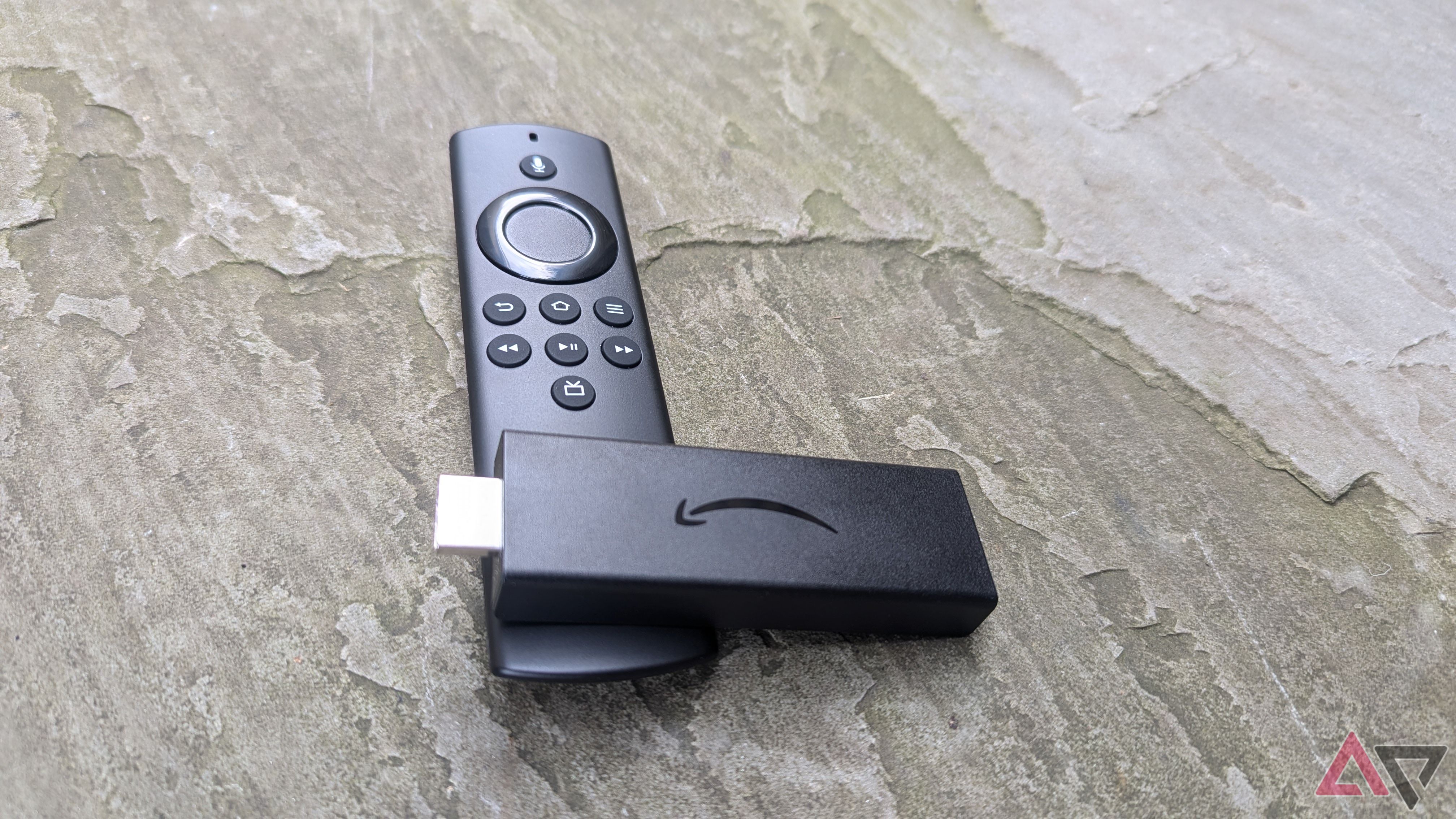 Amazon Fire TV Stick Lite e Alexa Voice Remote Lite na calçada cinza 