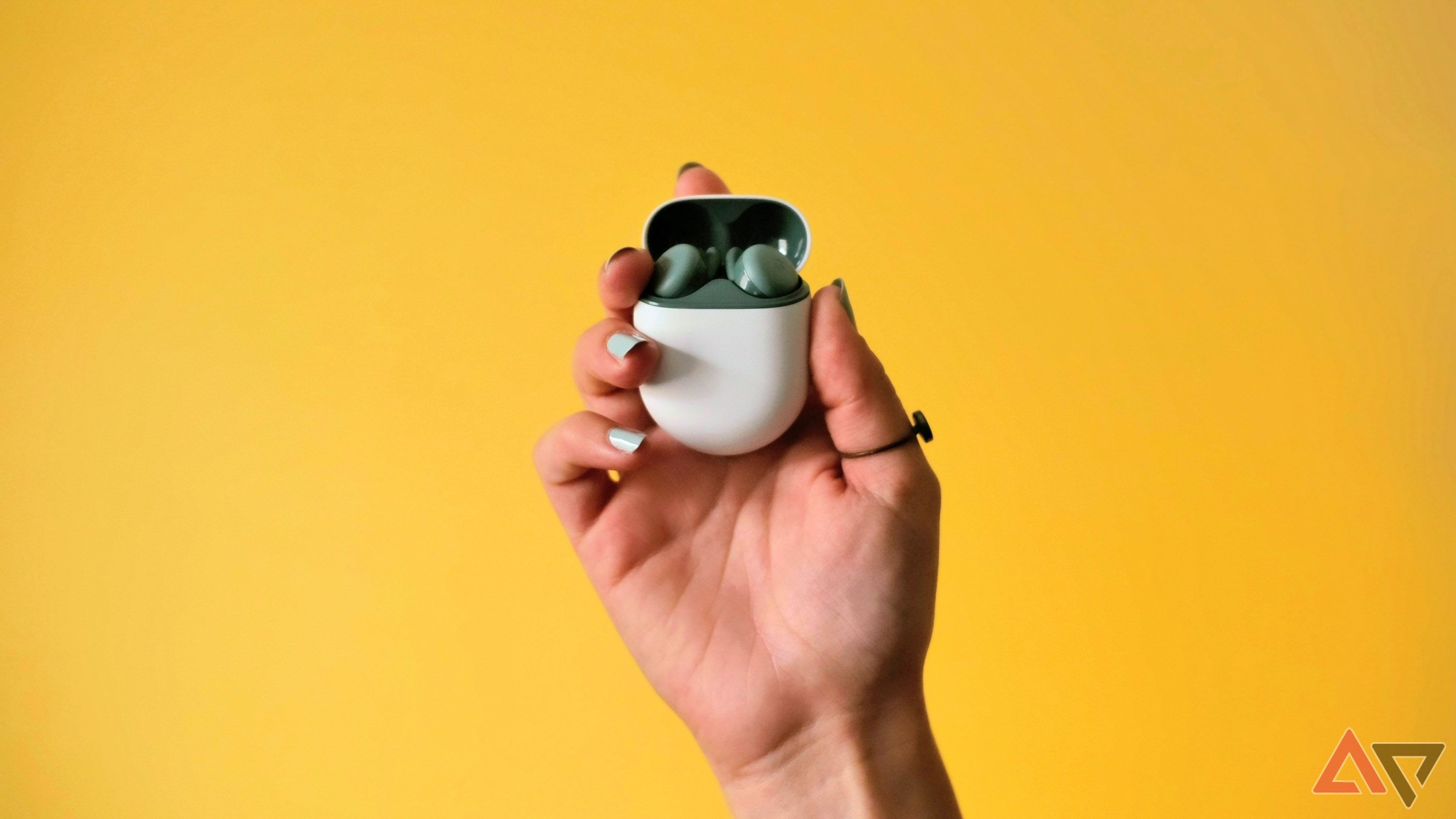 Os Pixel Buds A-Series na mão de uma mulher em frente a um fundo amarelo.