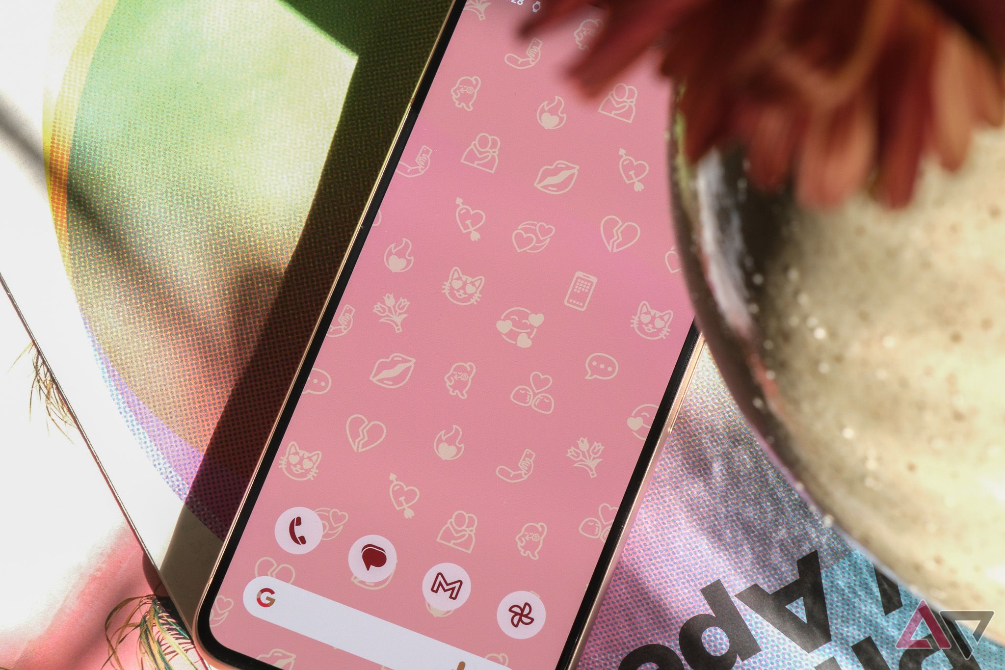 Google Pixel 8 mostrando emojis como papel de parede em um fundo rosa