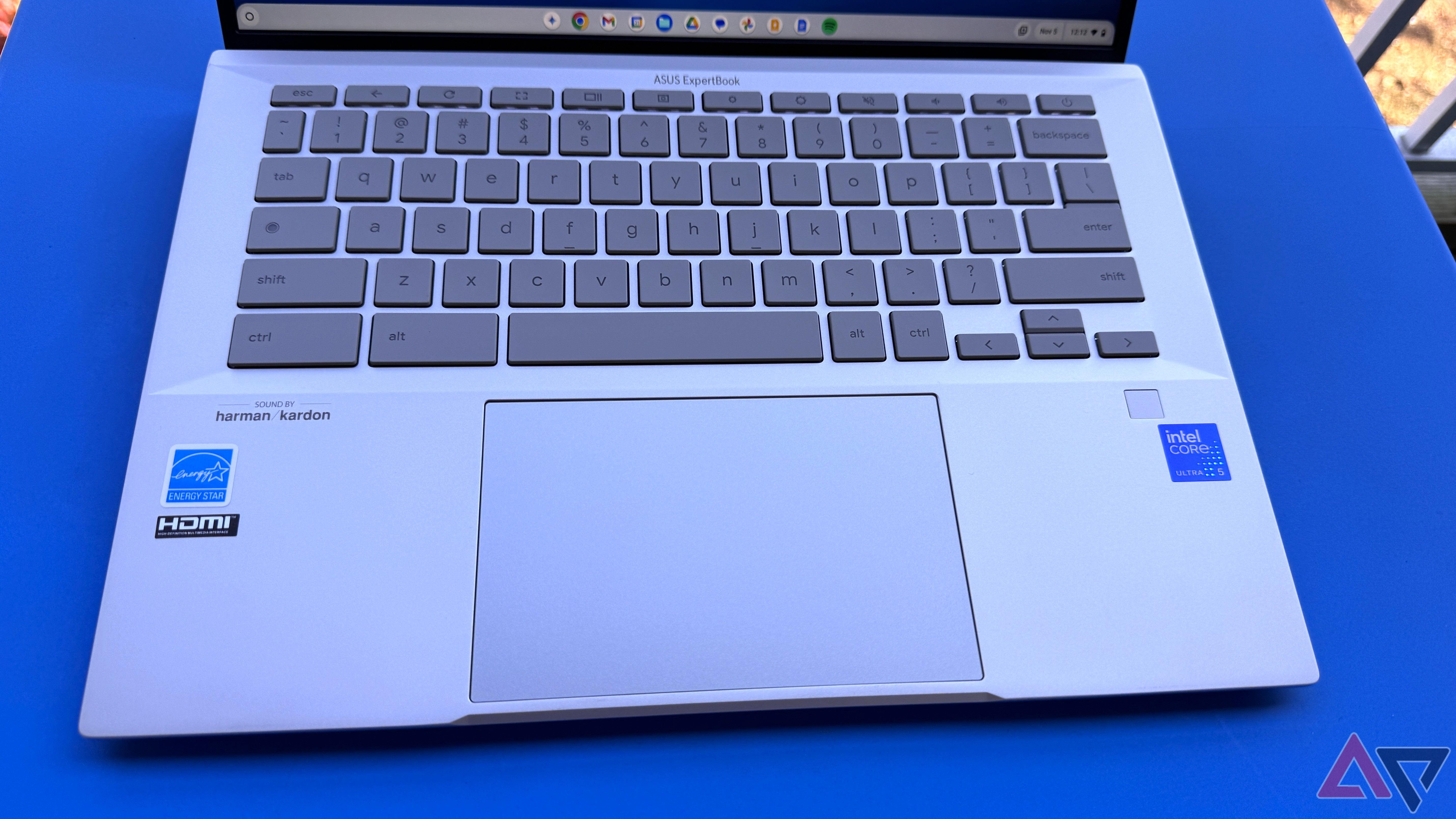 Teclado e Trackpad Asus Chromebook Plus CX54 em uma mesa azul.