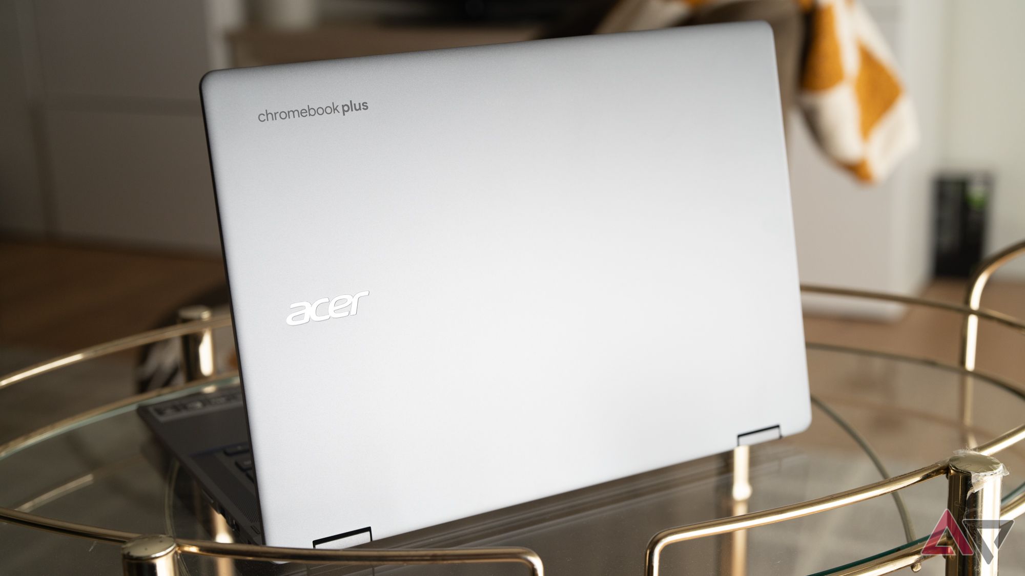 A parte traseira completa do Acer Chromebook Plus Spin 514 aberto sobre uma mesa de vidro