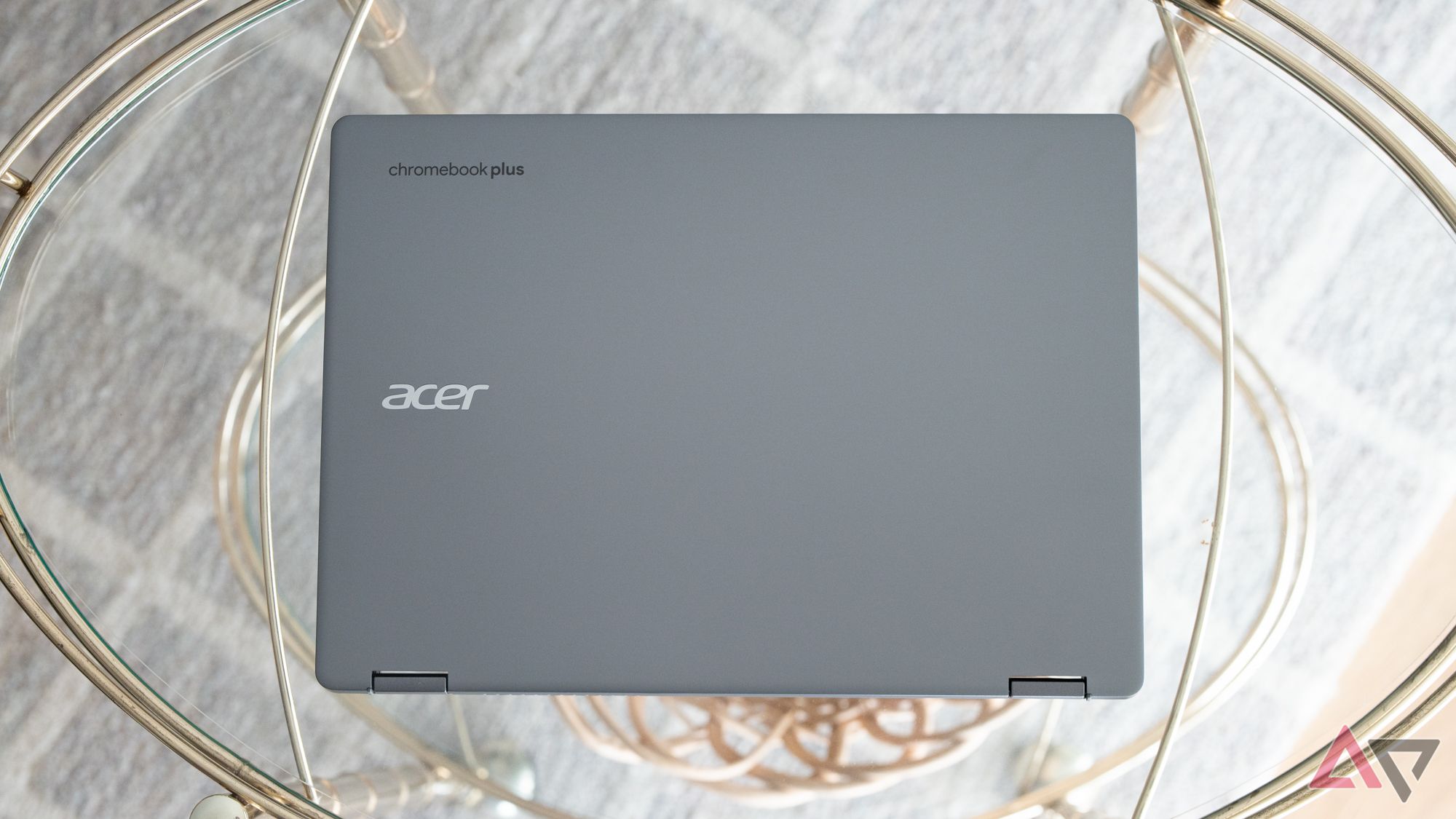 A parte traseira de um Acer Chromebook Plus Spin 514 fechado sobre uma mesa de vidro