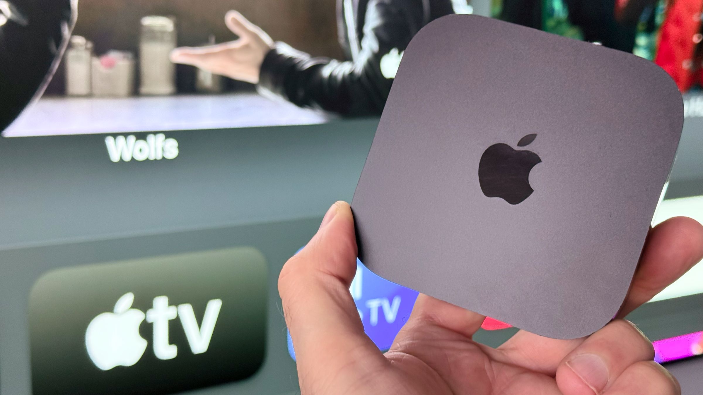 Apple TV 4K sendo segurada na frente de uma tela de TV