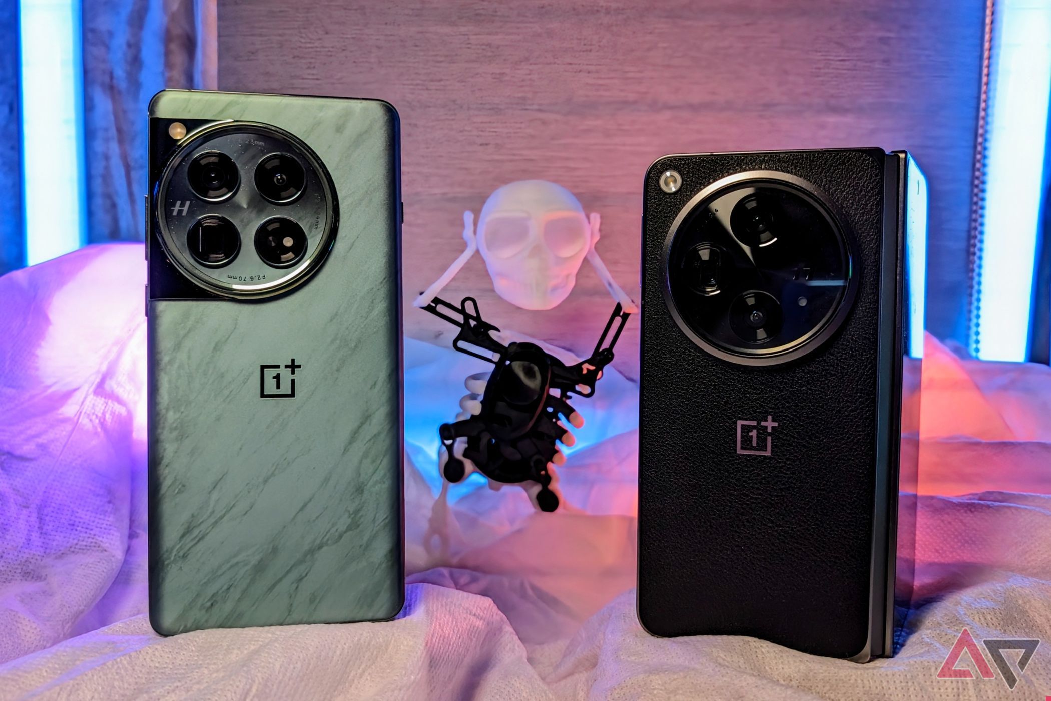 OnePlus 12 e OnePlus Openem uma mesa com um esqueleto atrás com luzes RGB