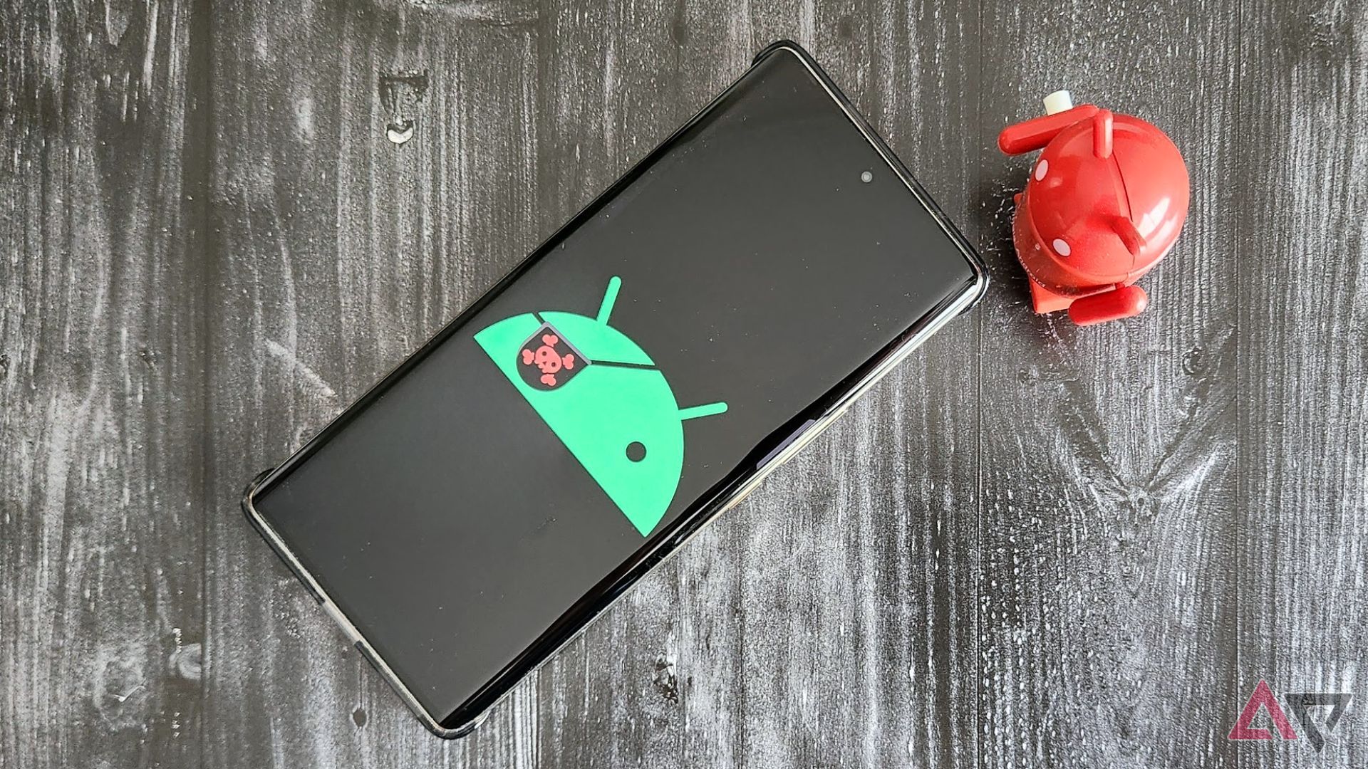 Um telefone com um logotipo pirata do Android em uma mesa ao lado de uma estatueta vermelha do Android