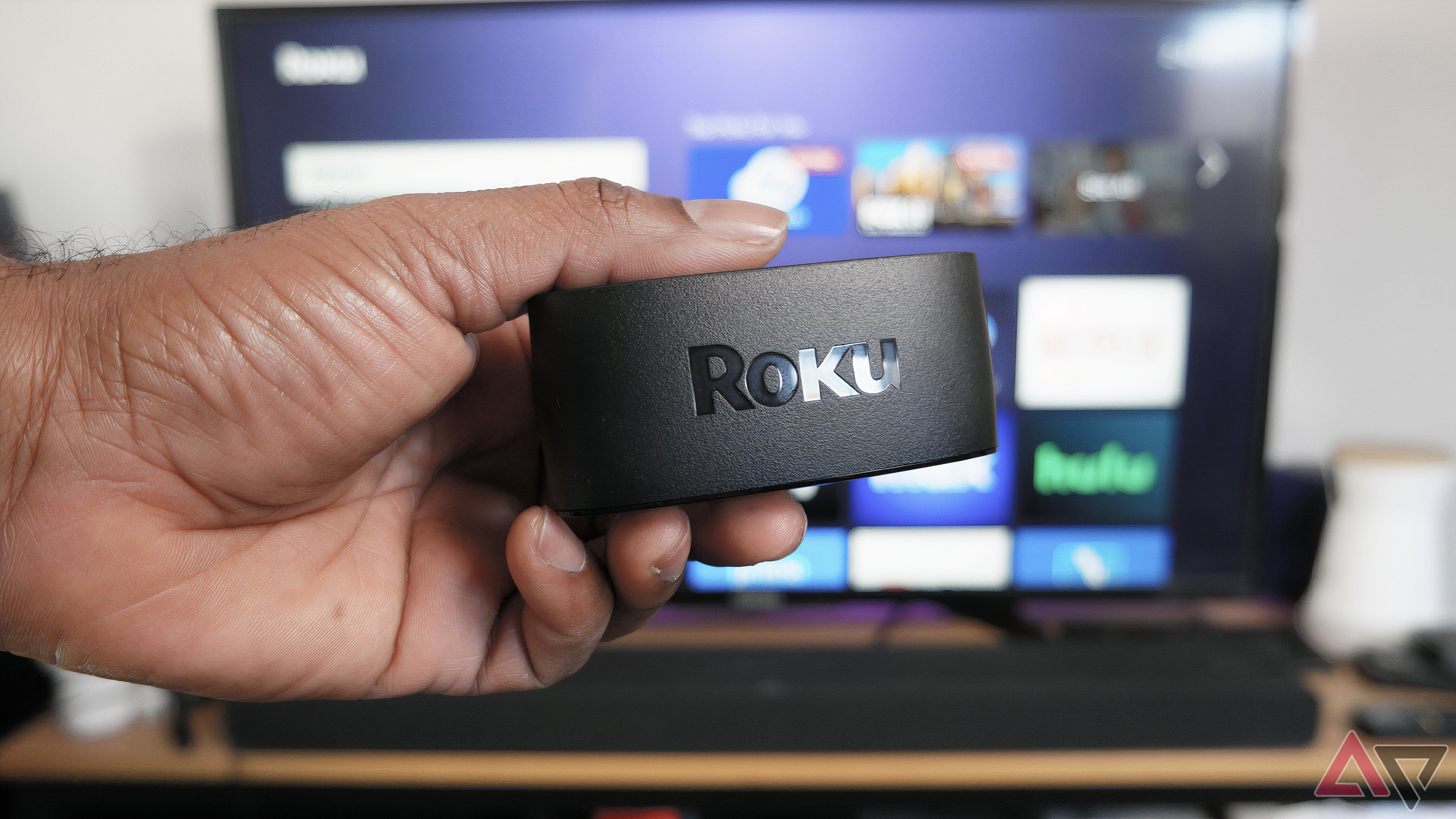 O dongle Roku Express 4K+ na frente de uma TV