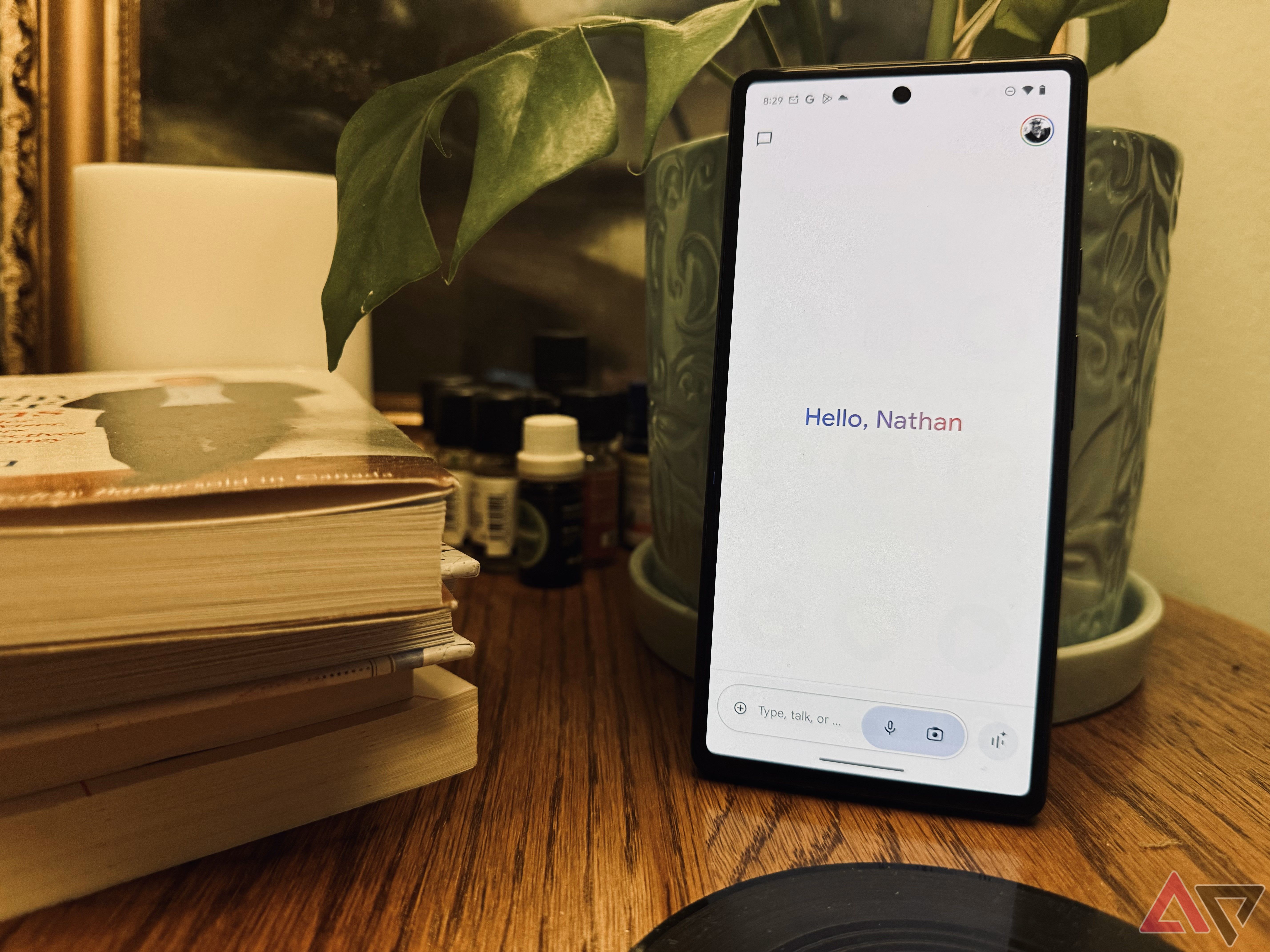 A nova interface do Google Gemini em um Pixel 6 em uma mesa com uma planta ao fundo e uma pilha de livros por perto.