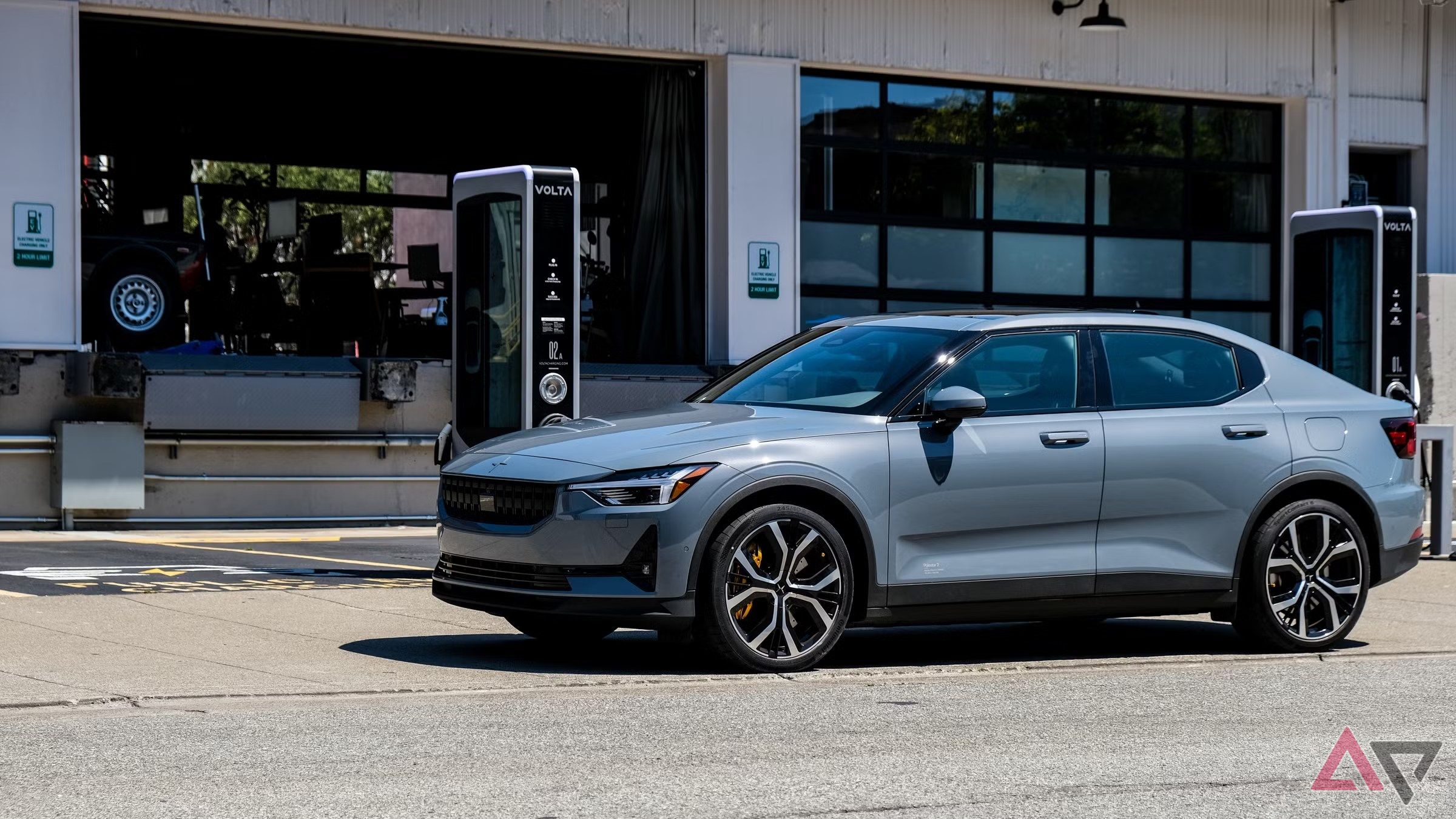 Um veículo elétrico estacionado fora de uma garagem perto de uma estação de carregamento