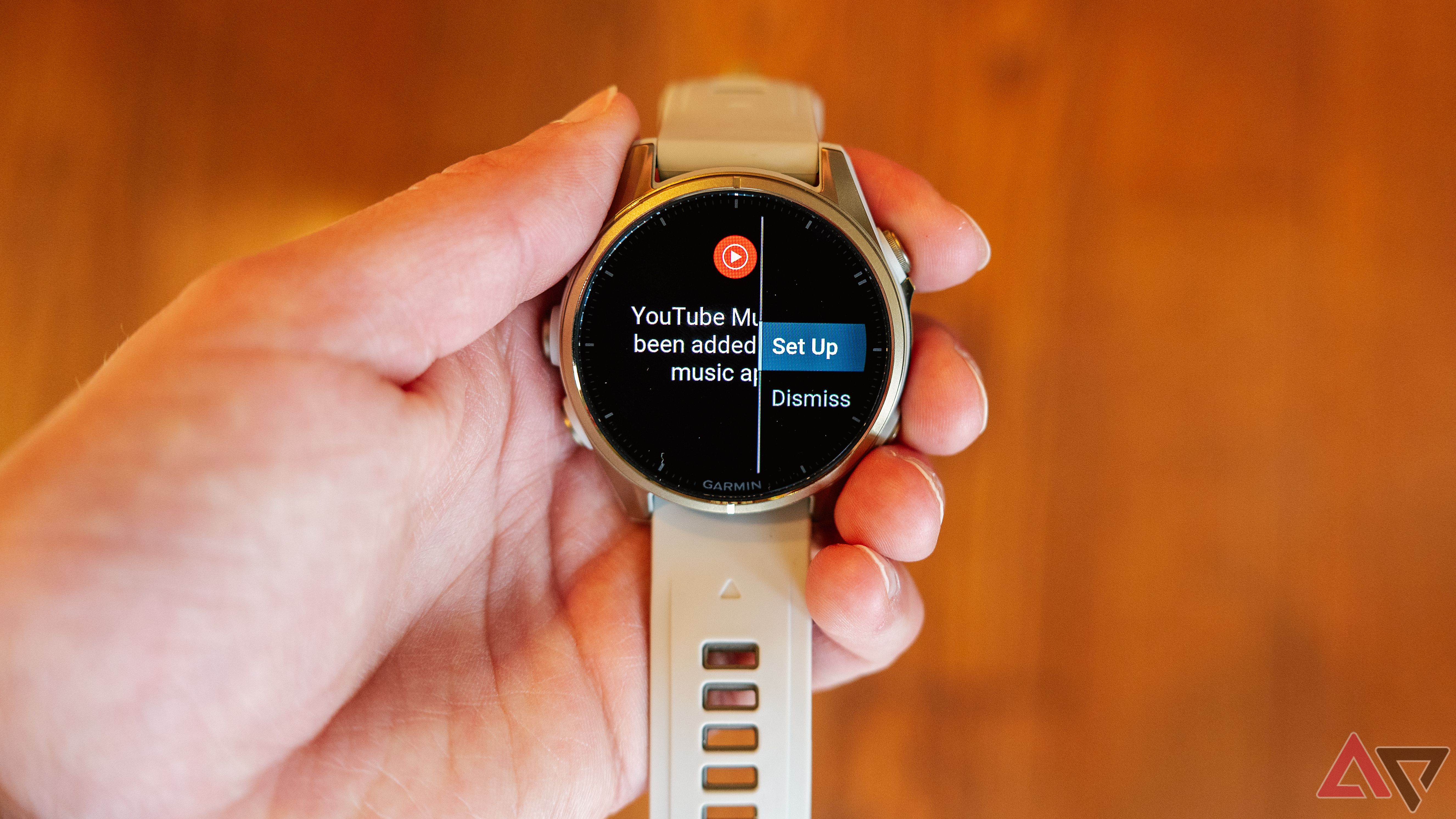 Uma mão segura o Garmin fenix 8 com a notificação de configuração do YouTube Music na tela.
