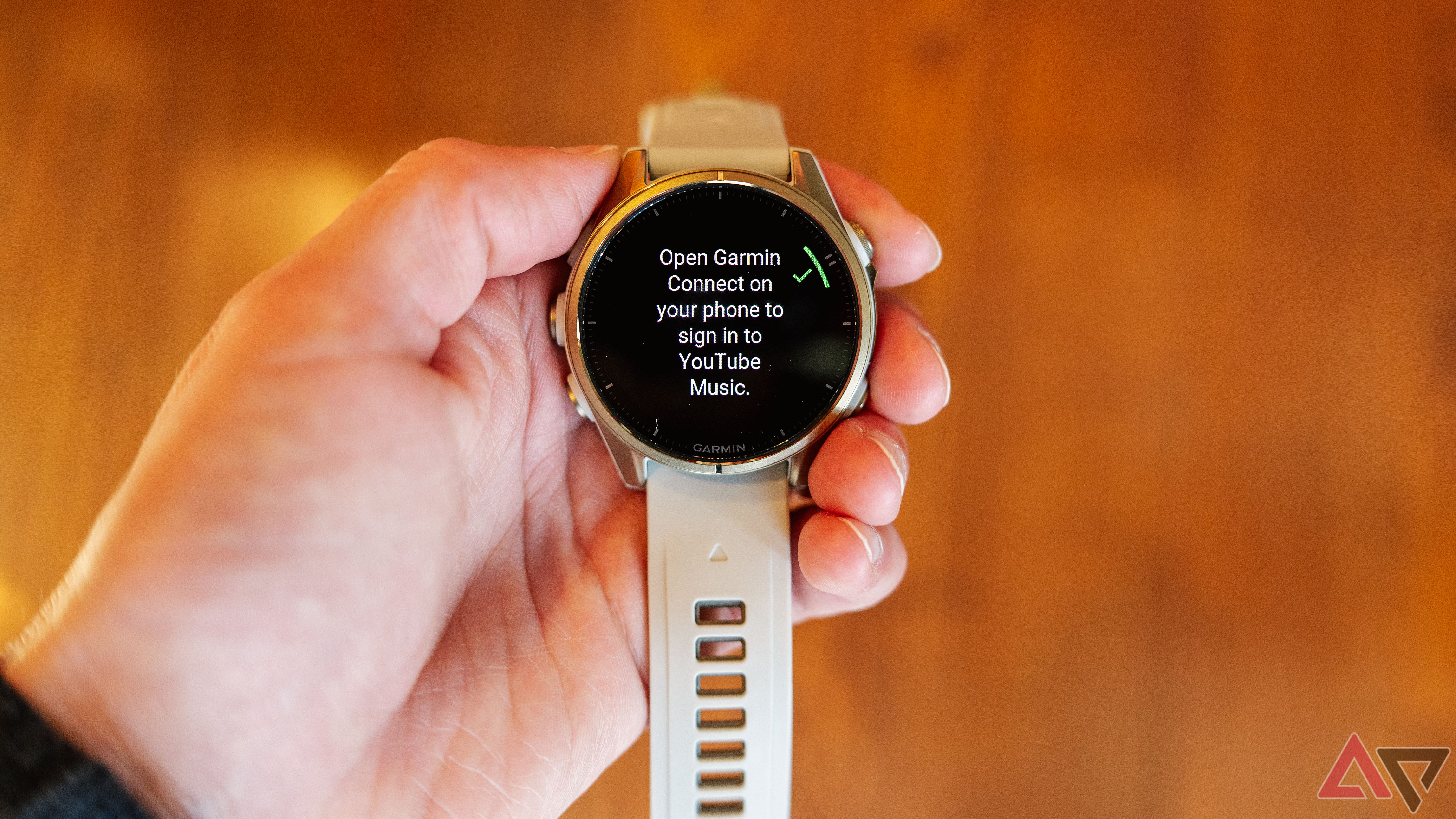 Uma mão segura o Garmin fenix 8 com a configuração do YouTube Music aparecendo na tela.