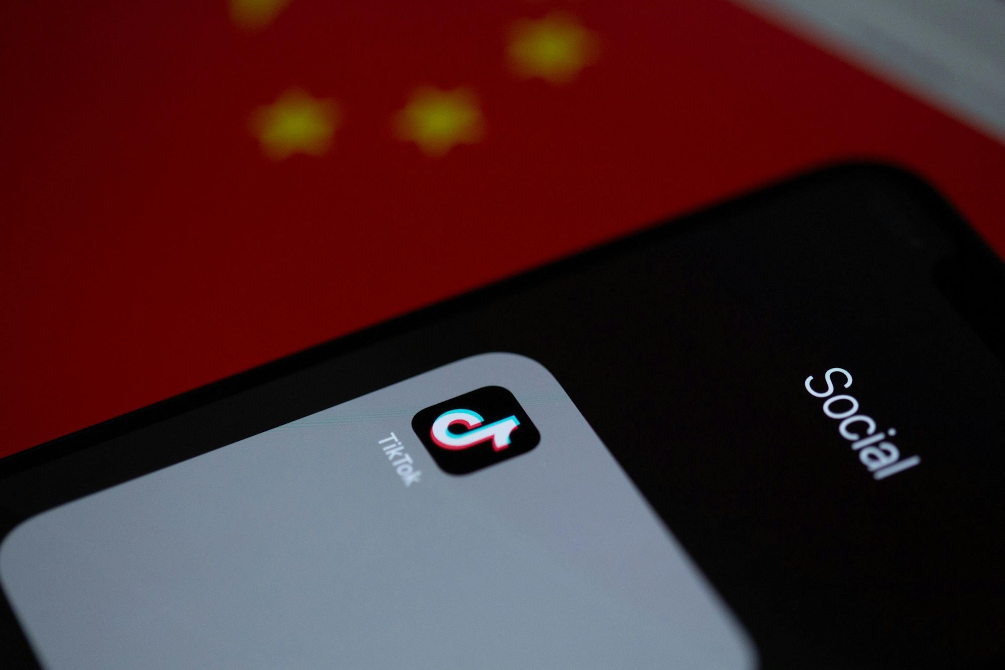 Close do ícone do aplicativo TikTok sobre um símbolo desfocado da bandeira chinesa