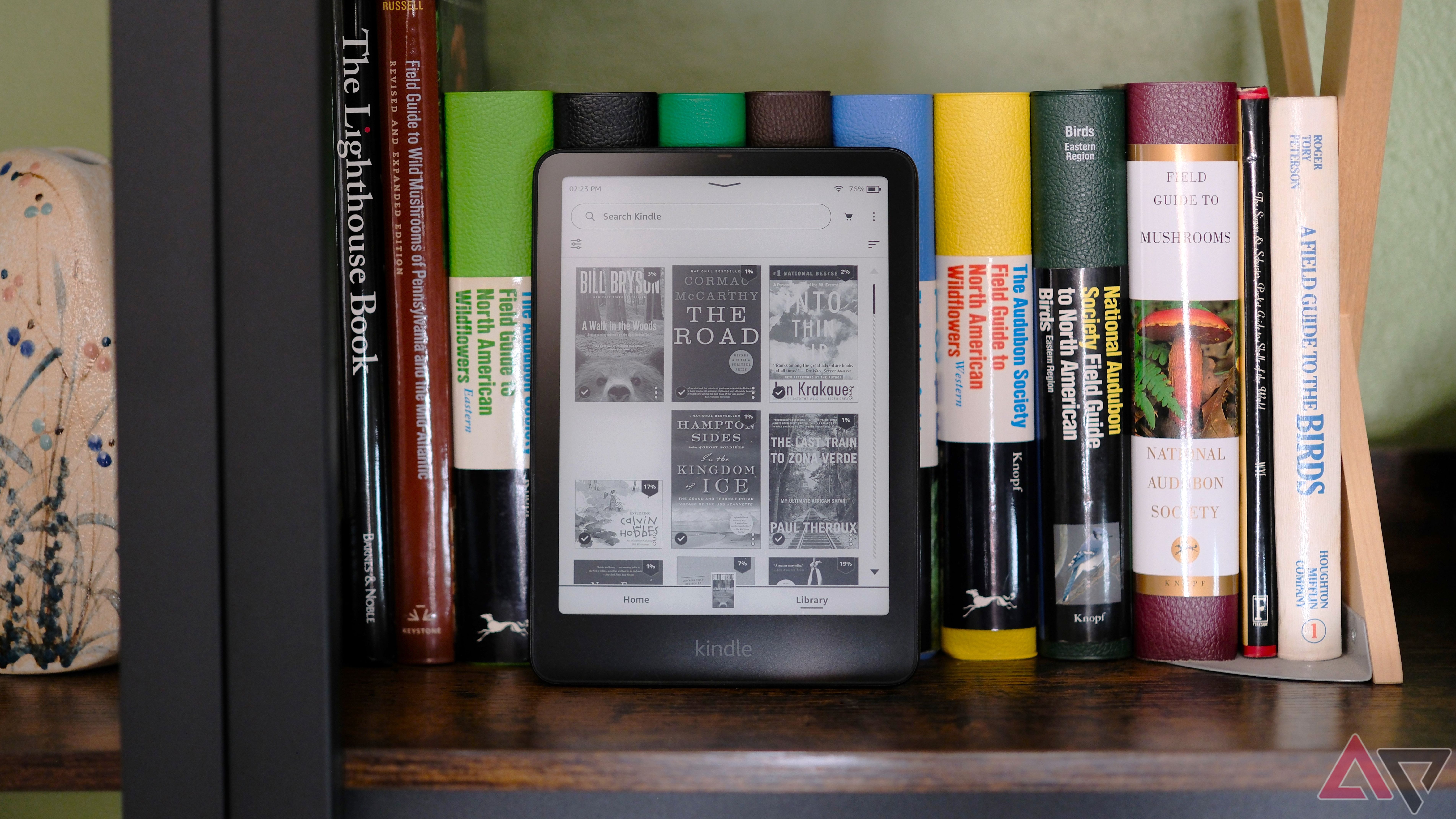 Kindle Paperwhite (2024) sentado na estante mostrando a tela com a biblioteca