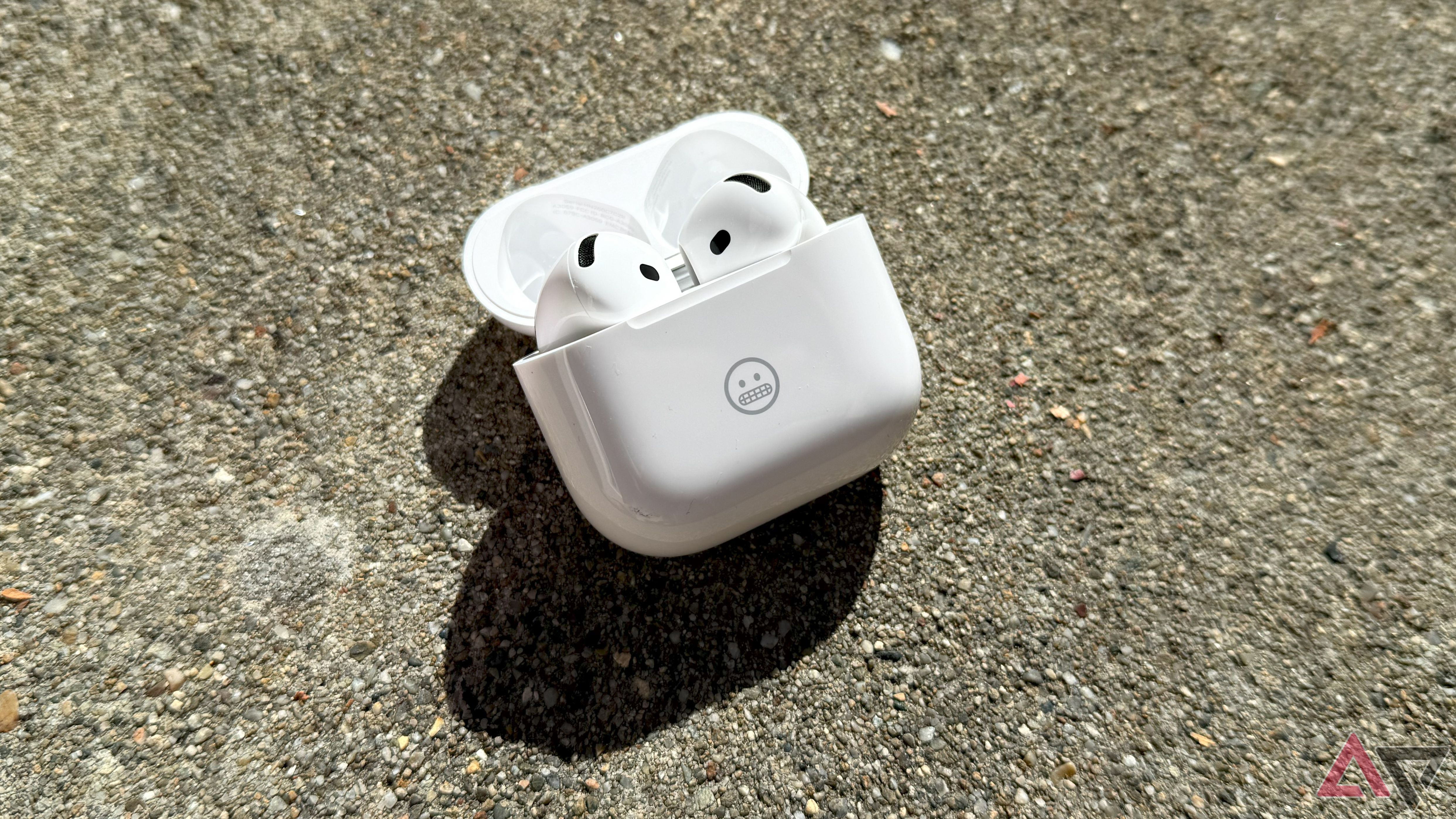 Uma imagem de cima para baixo dos AirPods 4 em uma caixa aberta em uma superfície texturizada