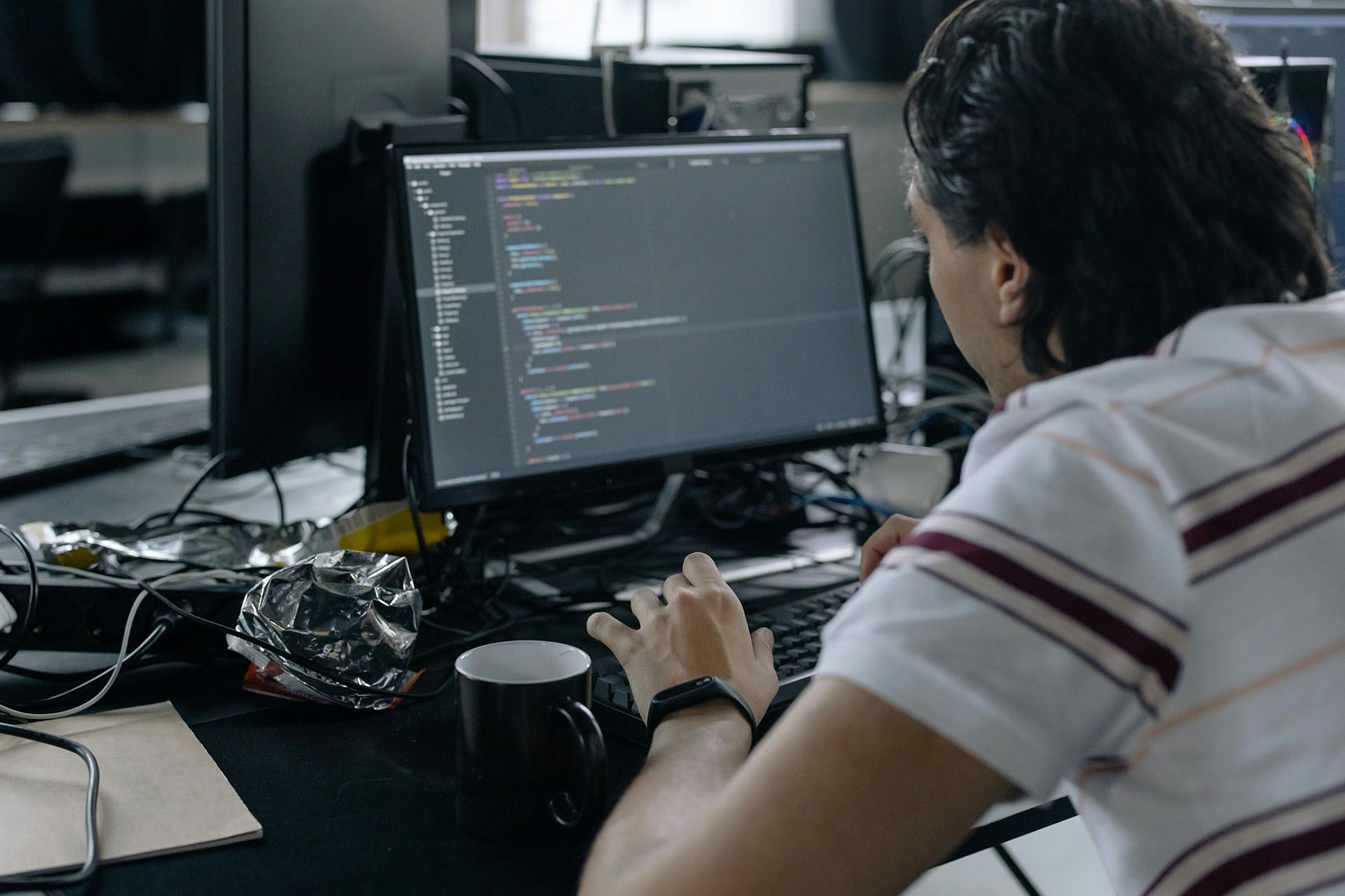 Um desenvolvedor sentado em frente a um computador que possui código na tela